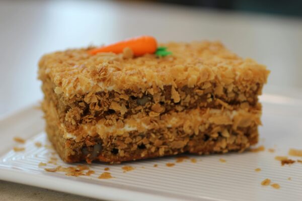 A slice of homemade carrot cake topped with cream frosting, perfect for dessert.