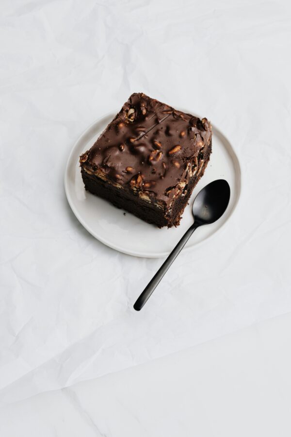A delectable piece of chocolate cake with nuts on a white plate.
