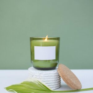 Minimalist candle with leaf on white surface, perfect for relaxation themes.